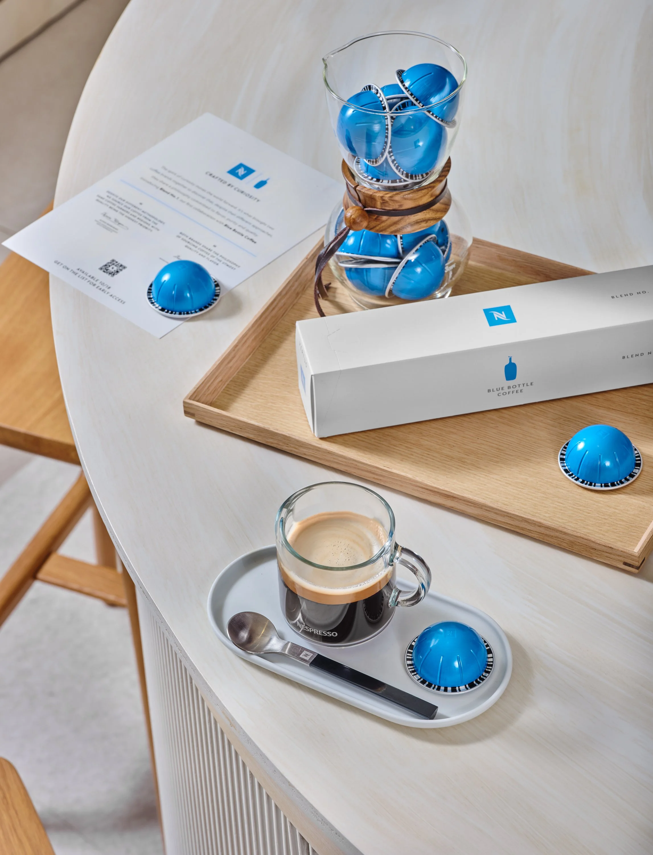 Tabletop detail — Blend No. 1 capsules in a glass carafe with espresso cup