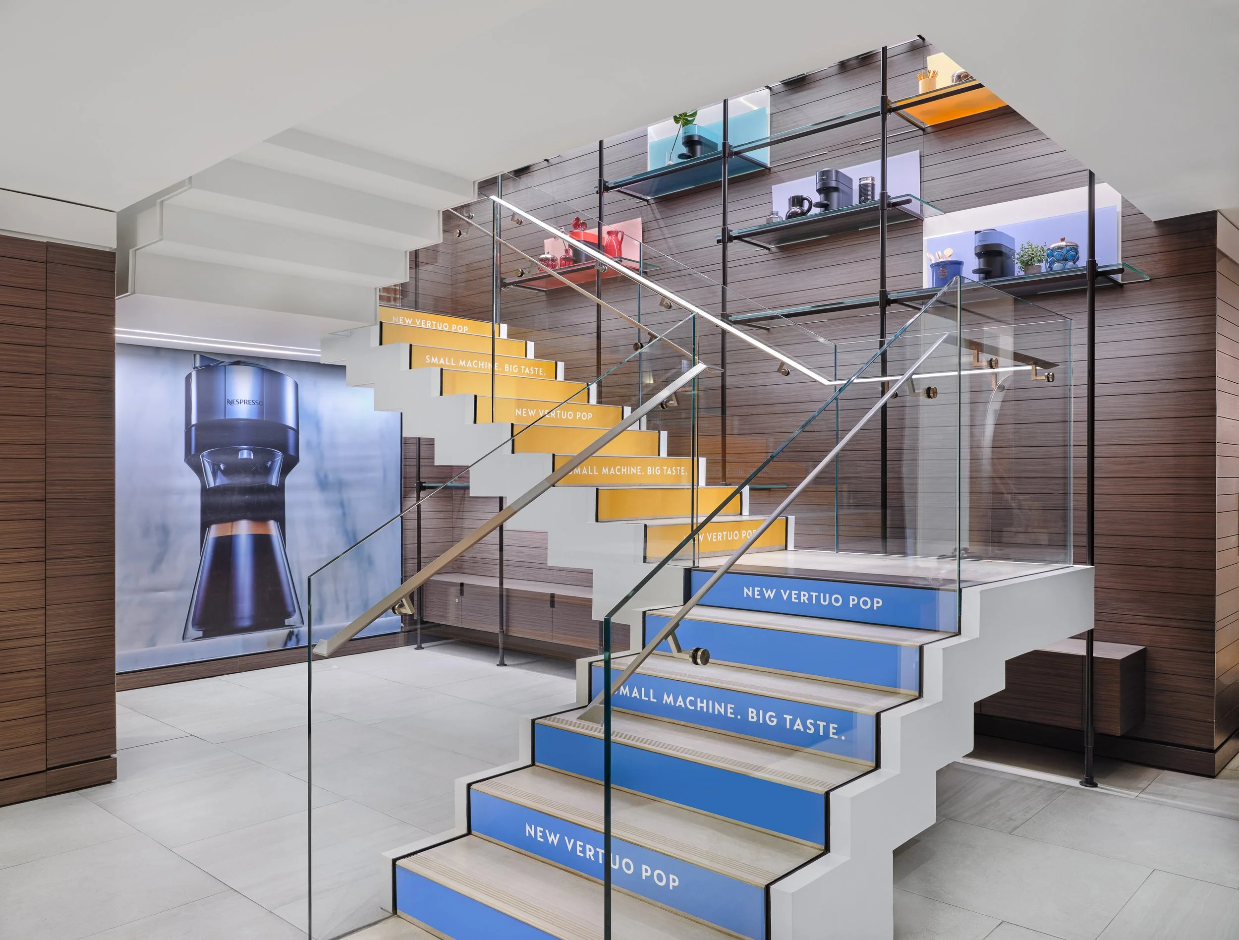 Boutique interior — staircase risers and arched display shelving carrying the Vertuo Pop campaign typography